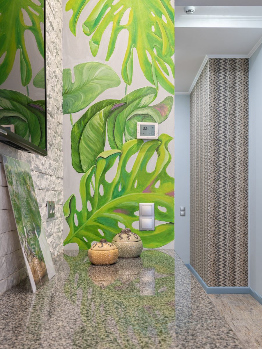 Hallway with an oversized green monstera-leaf mural wallpaper and a terrazzo floor