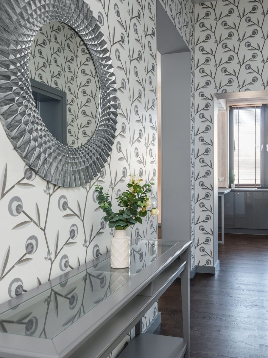 Hallway with a grey leaf-and-branch wallpaper, a sunburst mirror and a grey console table