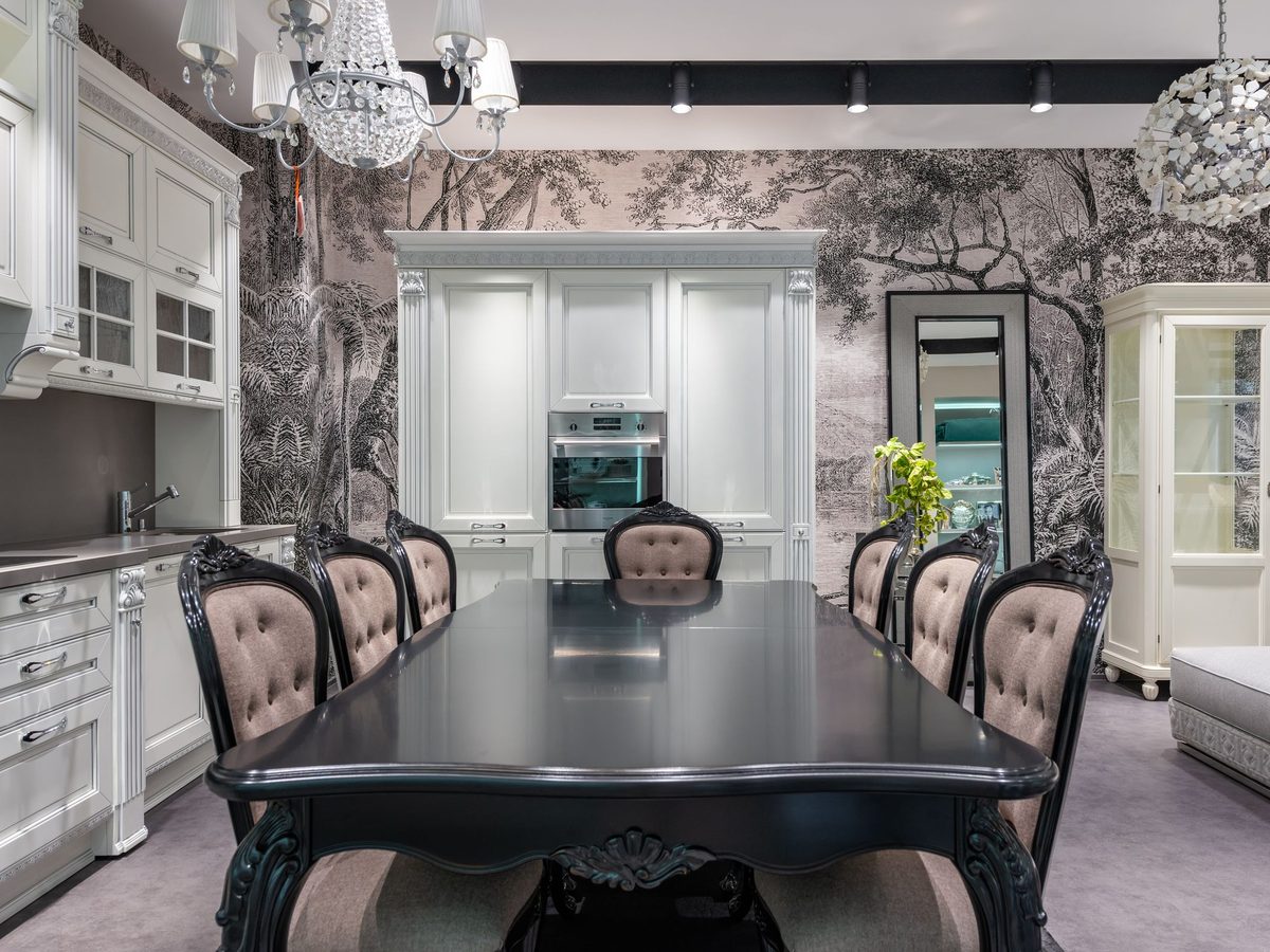 Open kitchen and dining room with a grey tree-silhouette mural wallpaper, a black dining table and upholstered chairs