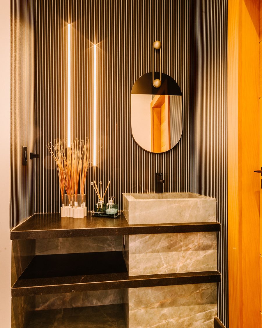 Compact powder room with a dark pinstripe wallcovering, stone vessel sink and an oval mirror